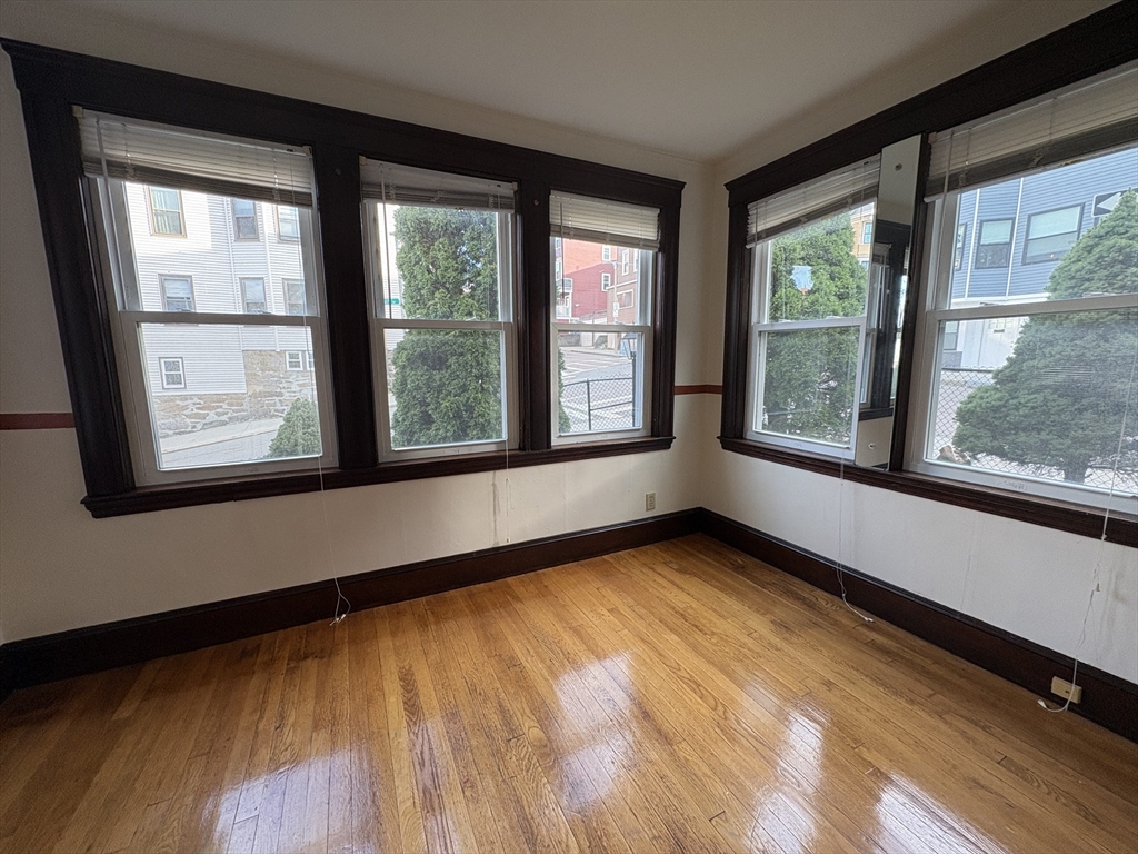 155-157 Hillside Street, Unit 1 Boston, MA 02120 - Photo 7 of 18 a view of an empty room with a window and wooden floor