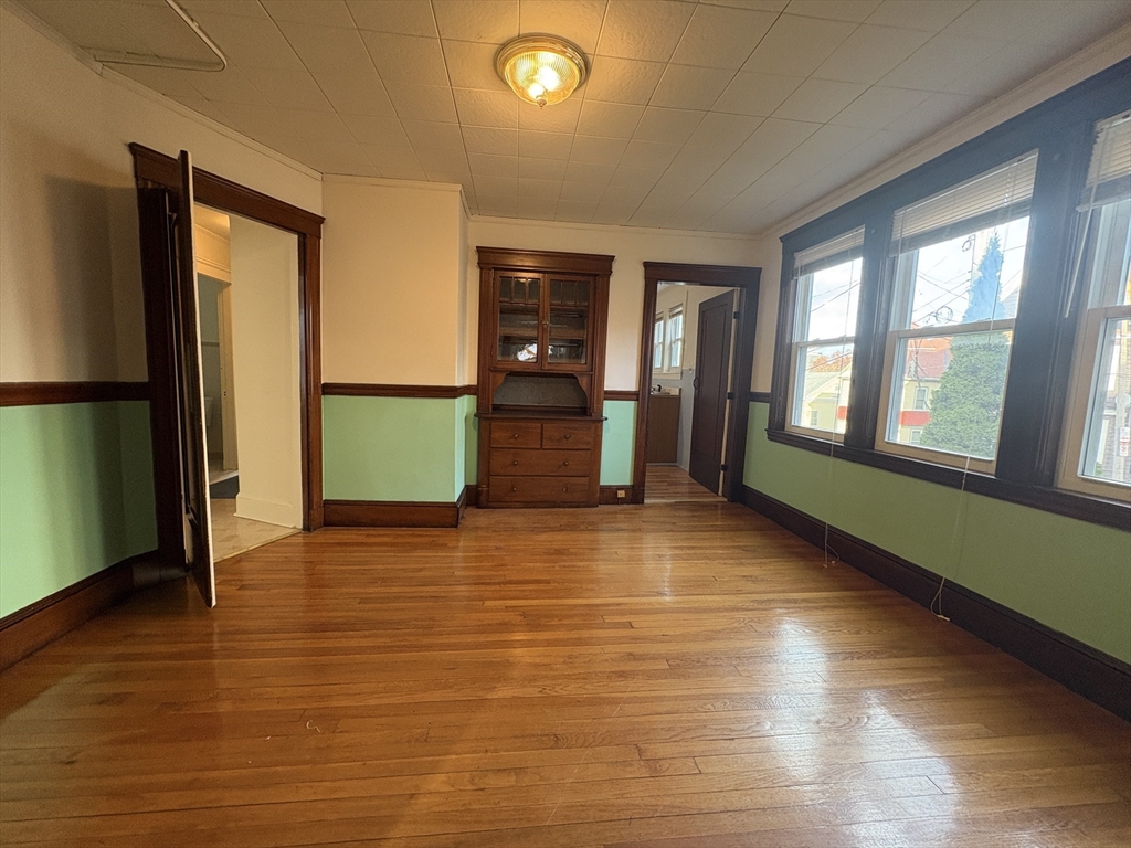 155-157 Hillside Street, Unit 1 Boston, MA 02120 - Photo 9 of 18 a view of an empty room with window and wooden floor
