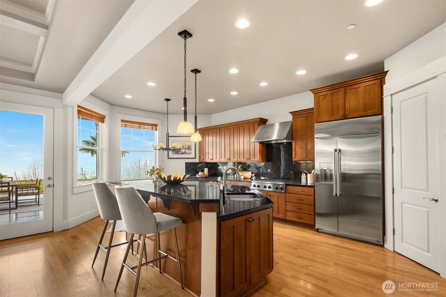 1500 South 5th Place Renton, WA 98057 - Photo 10 of 40 a kitchen with stainless steel appliances kitchen island granite countertop a refrigerator a stove a sink a dining table and chairs with wooden floor