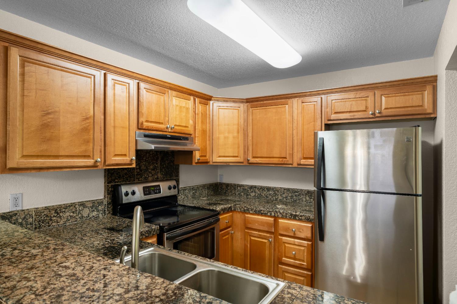 11150 Trinity River Drive, Unit 42 Rancho Cordova, CA 95670 - Photo 17 of 32 a kitchen with granite countertop a refrigerator and a sink