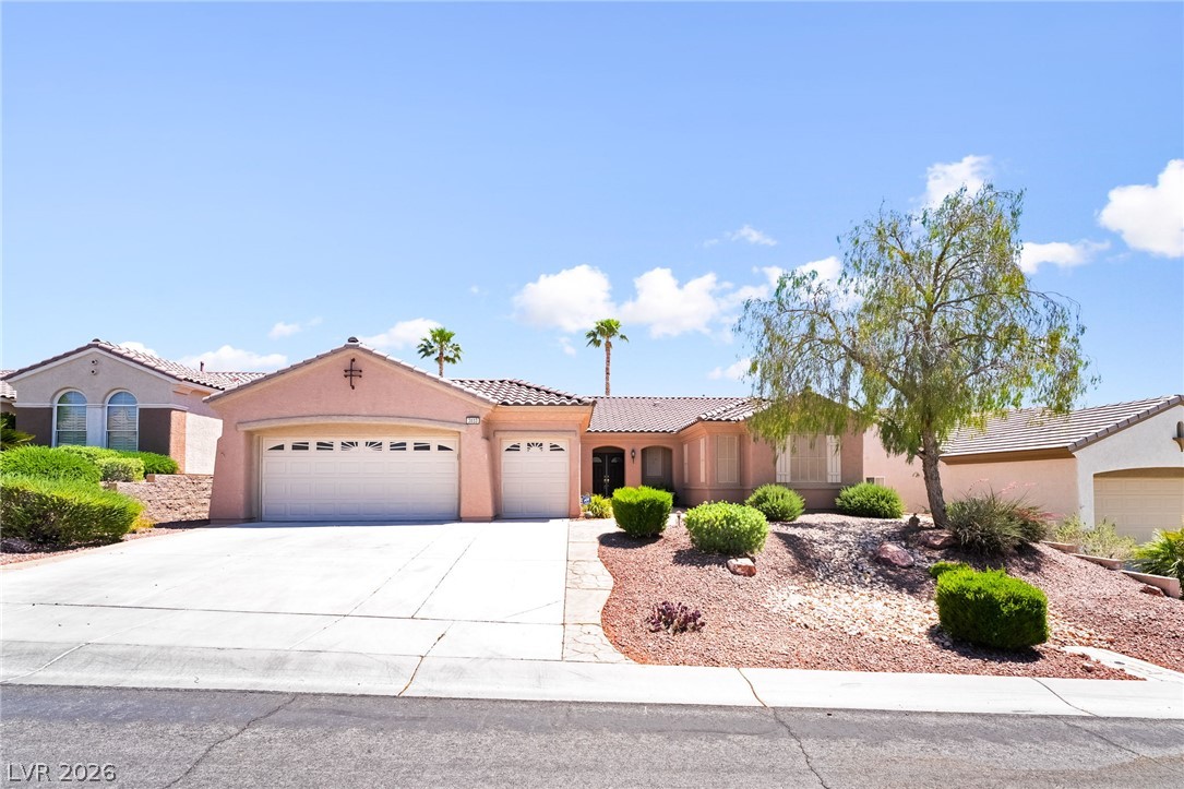 3033 Hartsville Road Henderson, NV 89052 - Photo 2 of 41 A well-maintained desert landscape frames this welcoming residence, featuring a clean concrete driveway and dual garage doors.