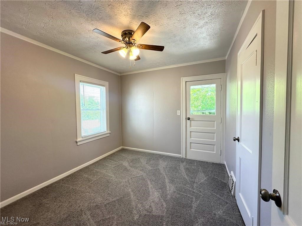3277 Cedarbrook Road Cleveland, OH 44118 - Photo 12 of 18 Spare room with plenty of natural light, ornamental molding, a textured ceiling, dark carpet, and ceiling fan