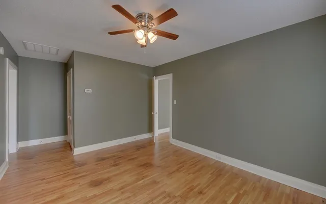 an empty room with wooden floor and a ceiling fan
