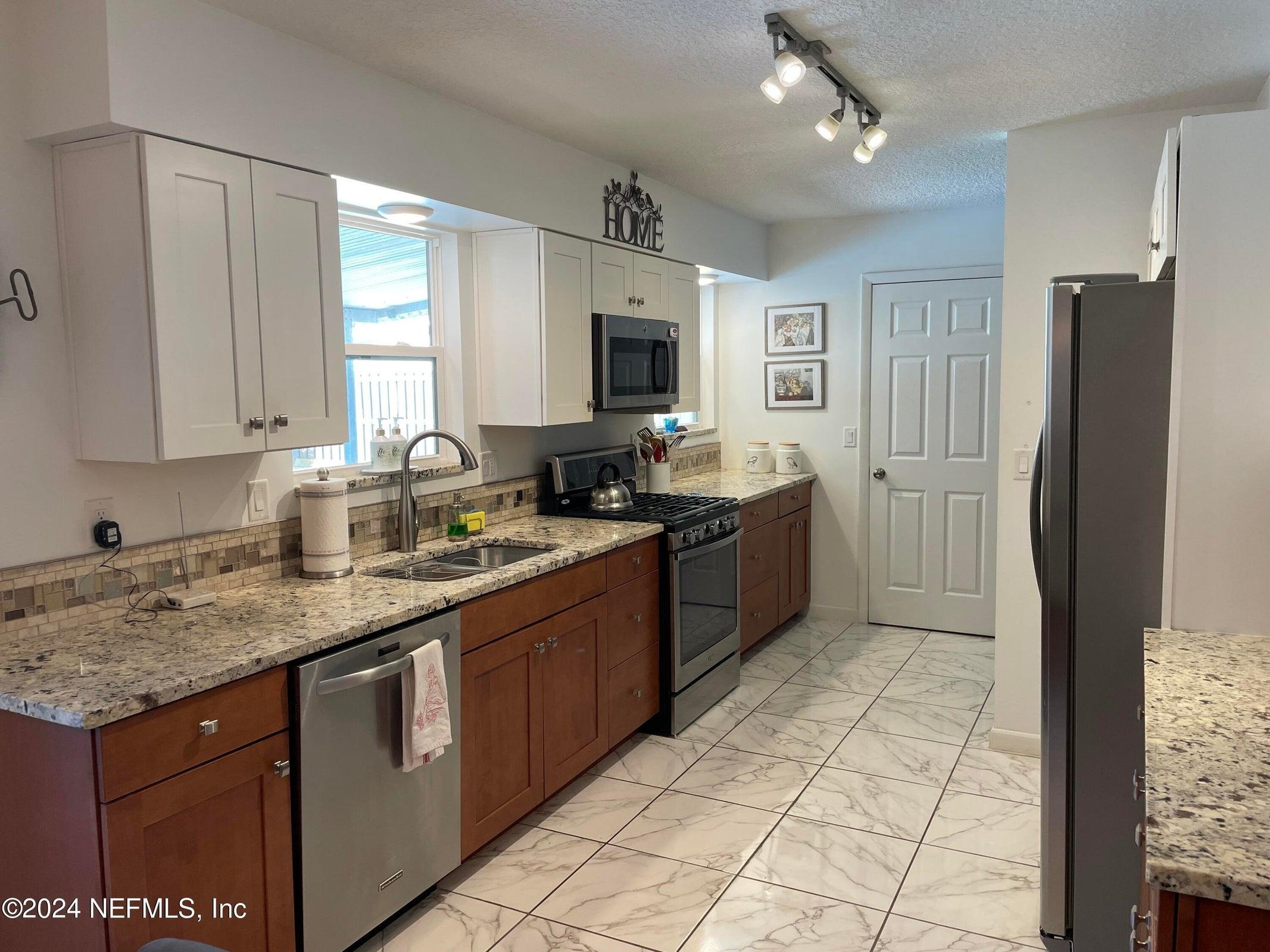 425 Gerona Road St. Augustine, FL 32086 - Photo 9 of 26 a kitchen with stainless steel appliances granite countertop a sink stove and refrigerator