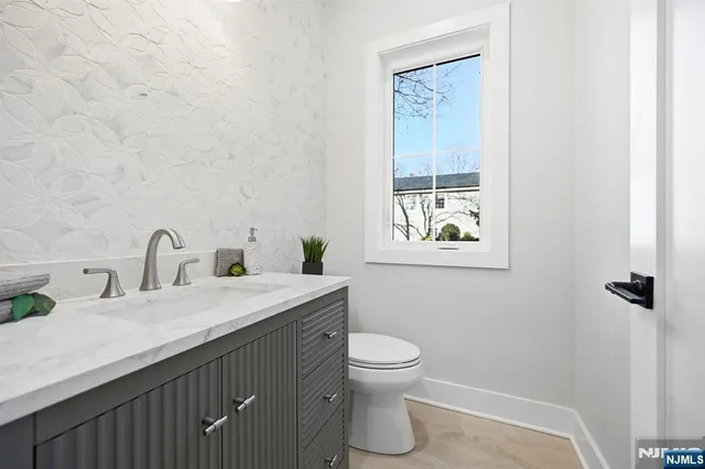a bathroom with a granite countertop sink toilet and painting on the wall