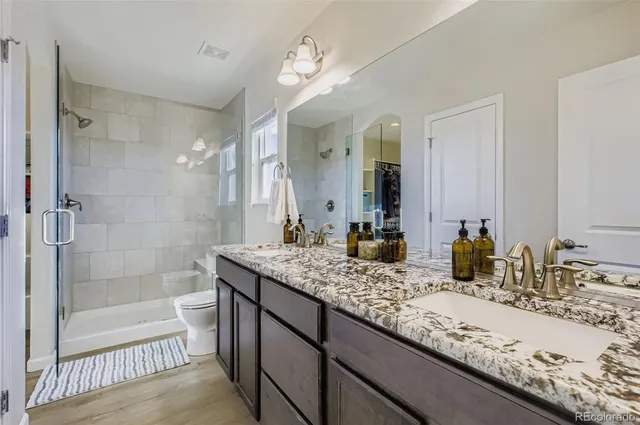 a bathroom with a granite countertop sink a mirror and a shower