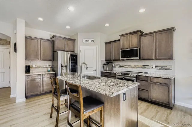a kitchen with a stove a sink a microwave a refrigerator and cabinets