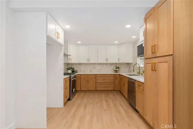 a kitchen with a sink a counter top space stainless steel appliances and cabinets