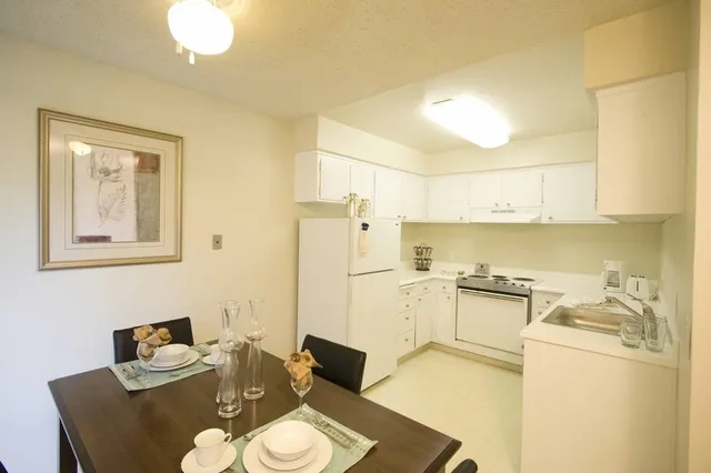 a kitchen with stainless steel appliances granite countertop a sink a stove a refrigerator a dining table and chairs with wooden floor