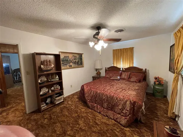 a spacious bedroom with a bed a dresser and book shelf
