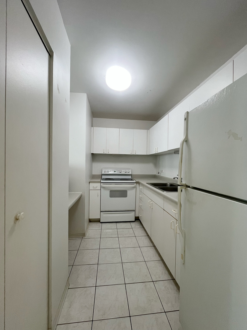 5320 North Sheridan Road, Unit 2110 Chicago, IL 60640 - Photo 6 of 16 a kitchen with a refrigerator and white cabinets