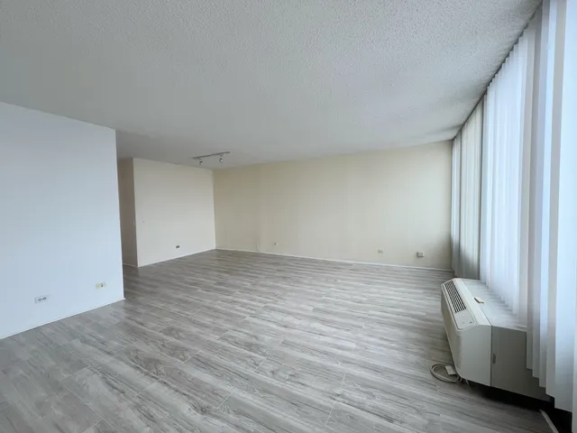 a view of an empty room with wooden floor and glass door