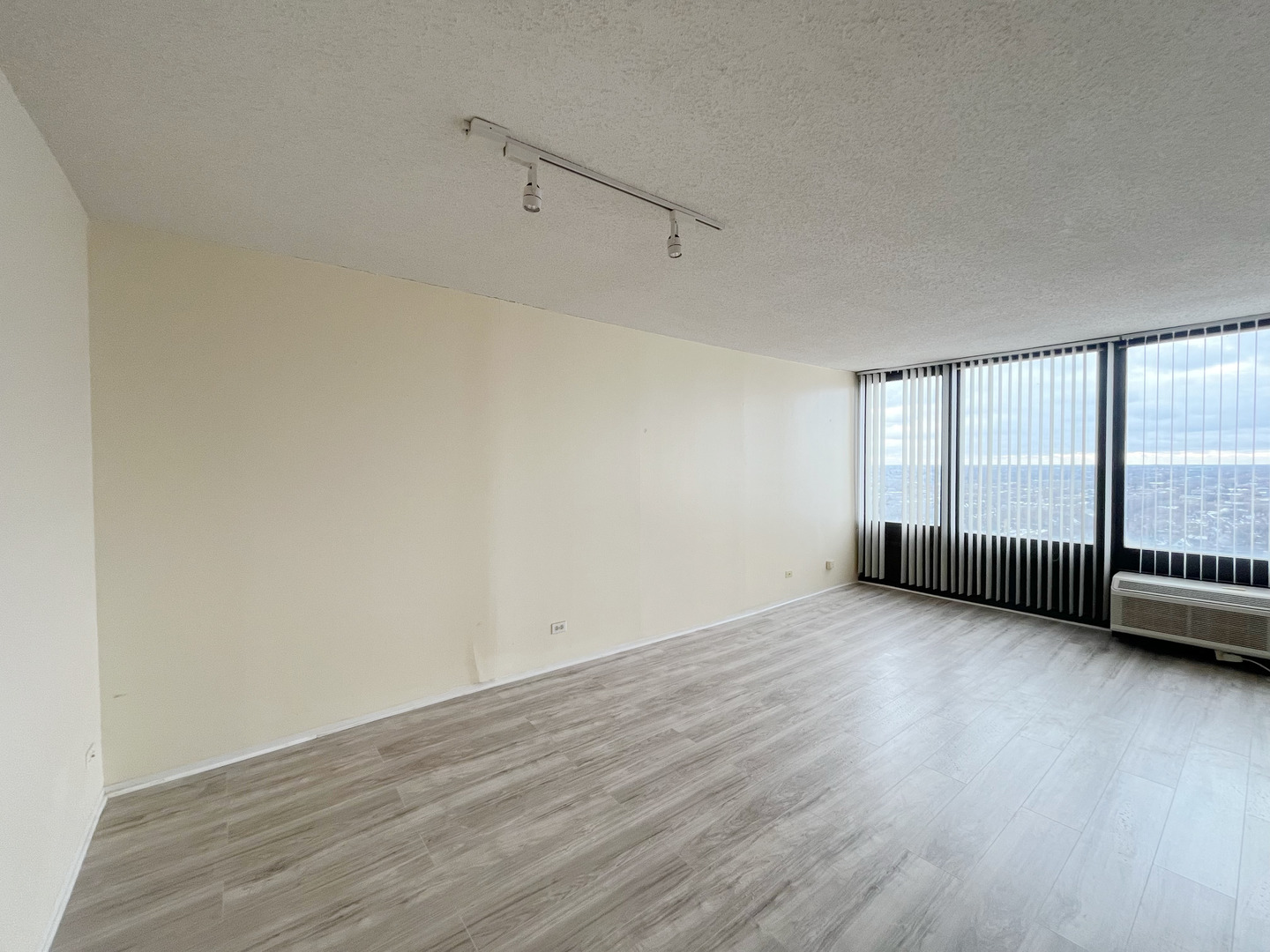 5320 North Sheridan Road, Unit 2110 Chicago, IL 60640 - Photo 9 of 16 a view of an empty room with wooden floor and a window