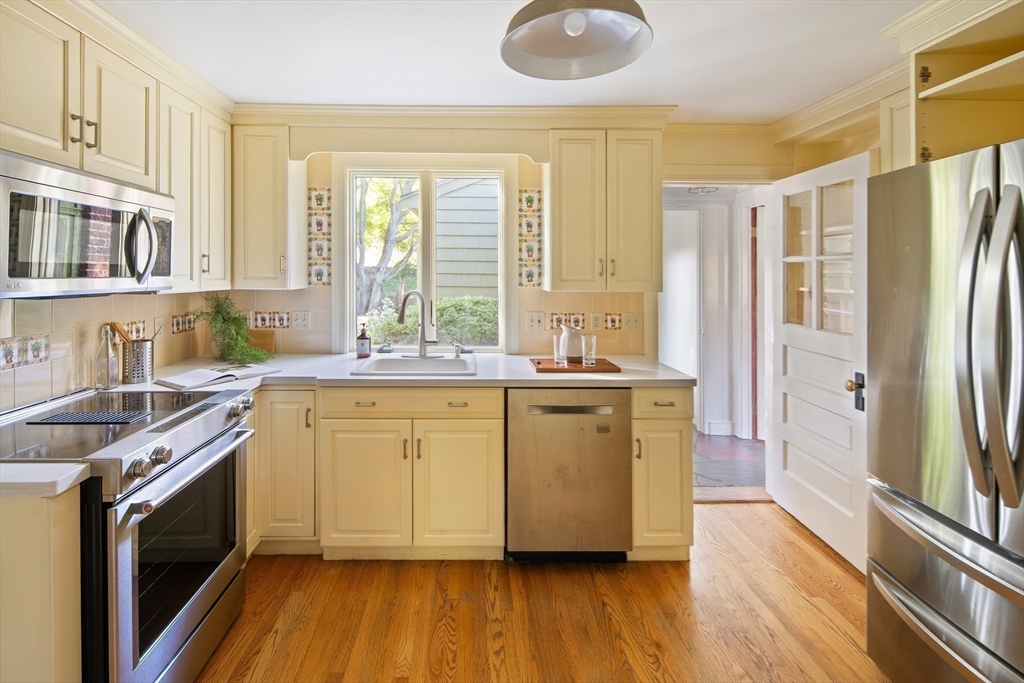 263 Common Street Belmont, MA 02478 - Photo 6 of 31 a kitchen with stainless steel appliances granite countertop a refrigerator a sink dishwasher a stove and white countertops with wooden floor