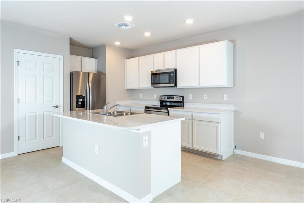 15307 Wildflower Circle Naples, FL 34119 - Photo 6 of 26 a kitchen with stainless steel appliances a refrigerator stove microwave and sink