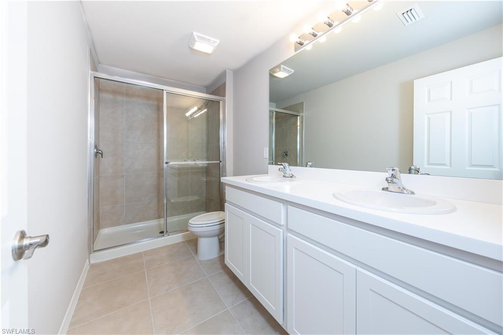 15307 Wildflower Circle Naples, FL 34119 - Photo 8 of 26 a bathroom with a double vanity sink toilet and shower