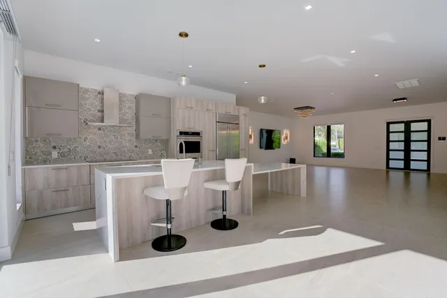 a kitchen with stainless steel appliances kitchen island granite countertop a table chairs and a refrigerator