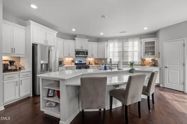 a kitchen with stainless steel appliances granite countertop a dining table chairs refrigerator microwave and cabinets
