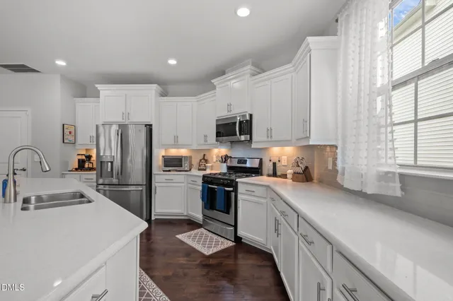 a view of a dining room with furniture a kitchen and chandelier