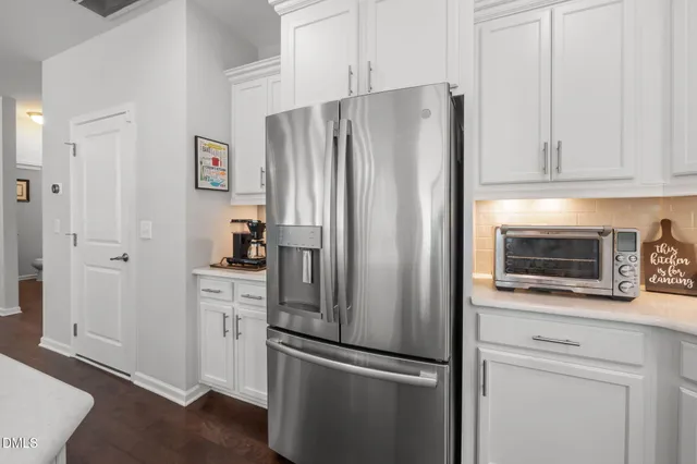 a kitchen with stainless steel appliances granite countertop a refrigerator stove a sink and white cabinets