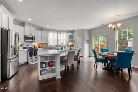 a kitchen with stainless steel appliances granite countertop a dining table chairs refrigerator microwave and cabinets