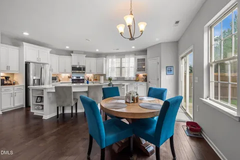 a kitchen with refrigerator a stove a sink and chairs
