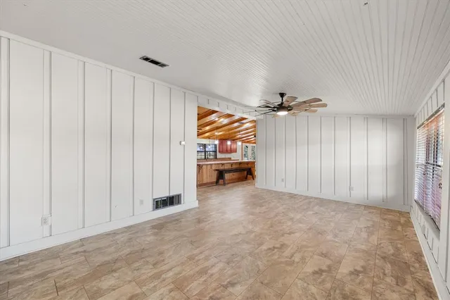 an empty room with windows and chandelier fan