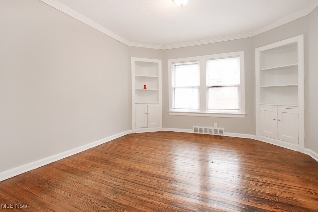 3973 Navahoe Road Cleveland, OH 44121 - Photo 12 of 14 Empty room featuring built in features, visible vents, baseboards, and dark wood-style floors