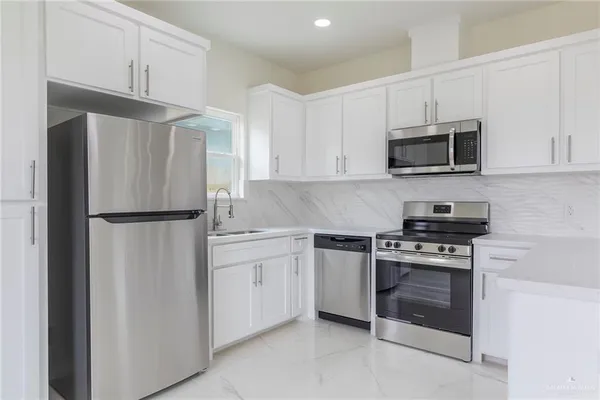 a kitchen with white cabinets and stainless steel appliances
