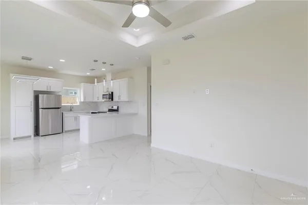 a large white kitchen with a refrigerator a stove top oven and white cabinets