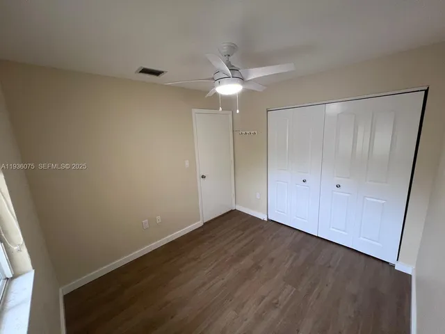 an empty room with wooden floor fan and windows
