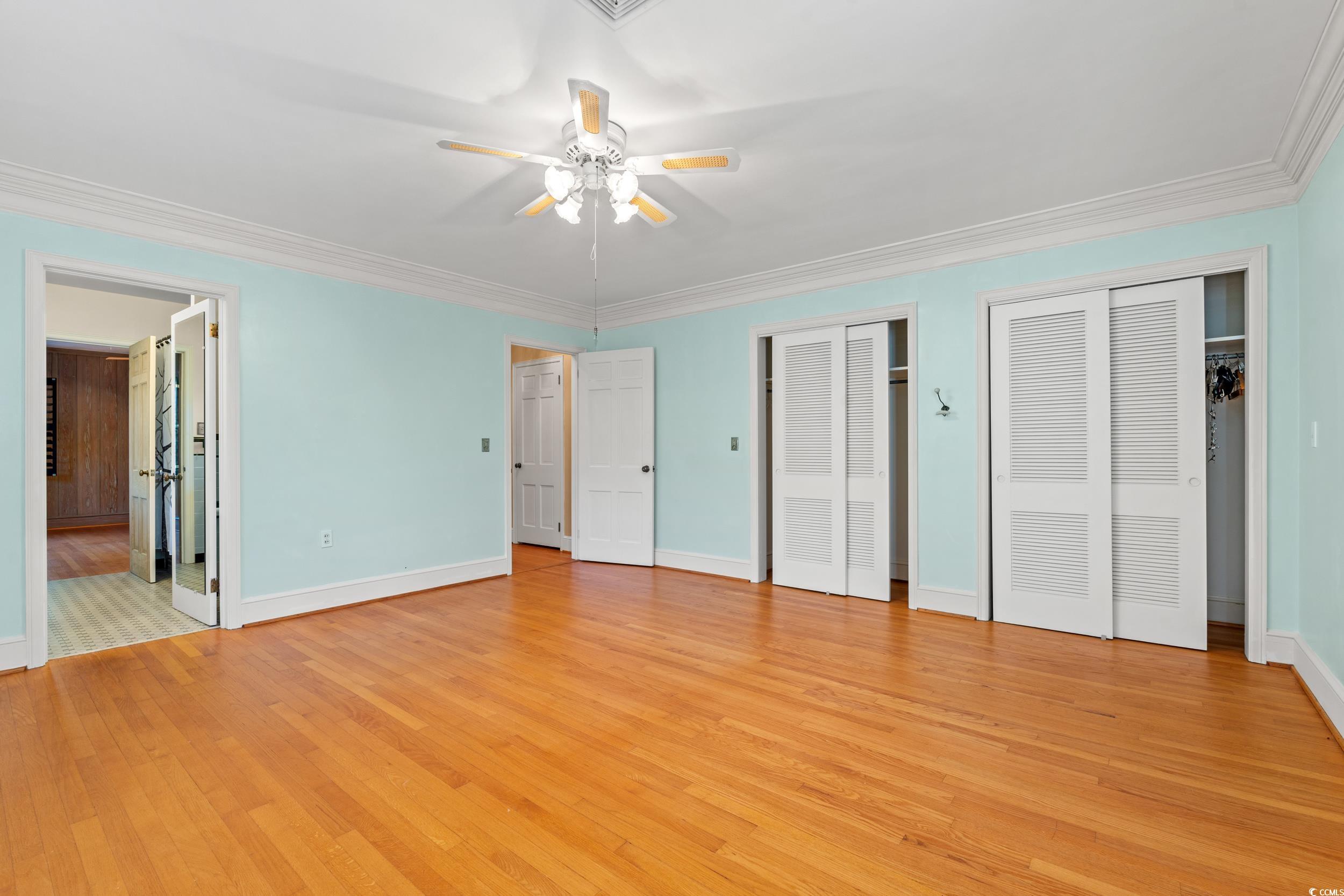 607 North Main Street Nichols, SC 29581 - Photo 18 of 39 Unfurnished bedroom featuring two closets, light wood-style flooring, ornamental molding, a ceiling fan, and connected bathroom