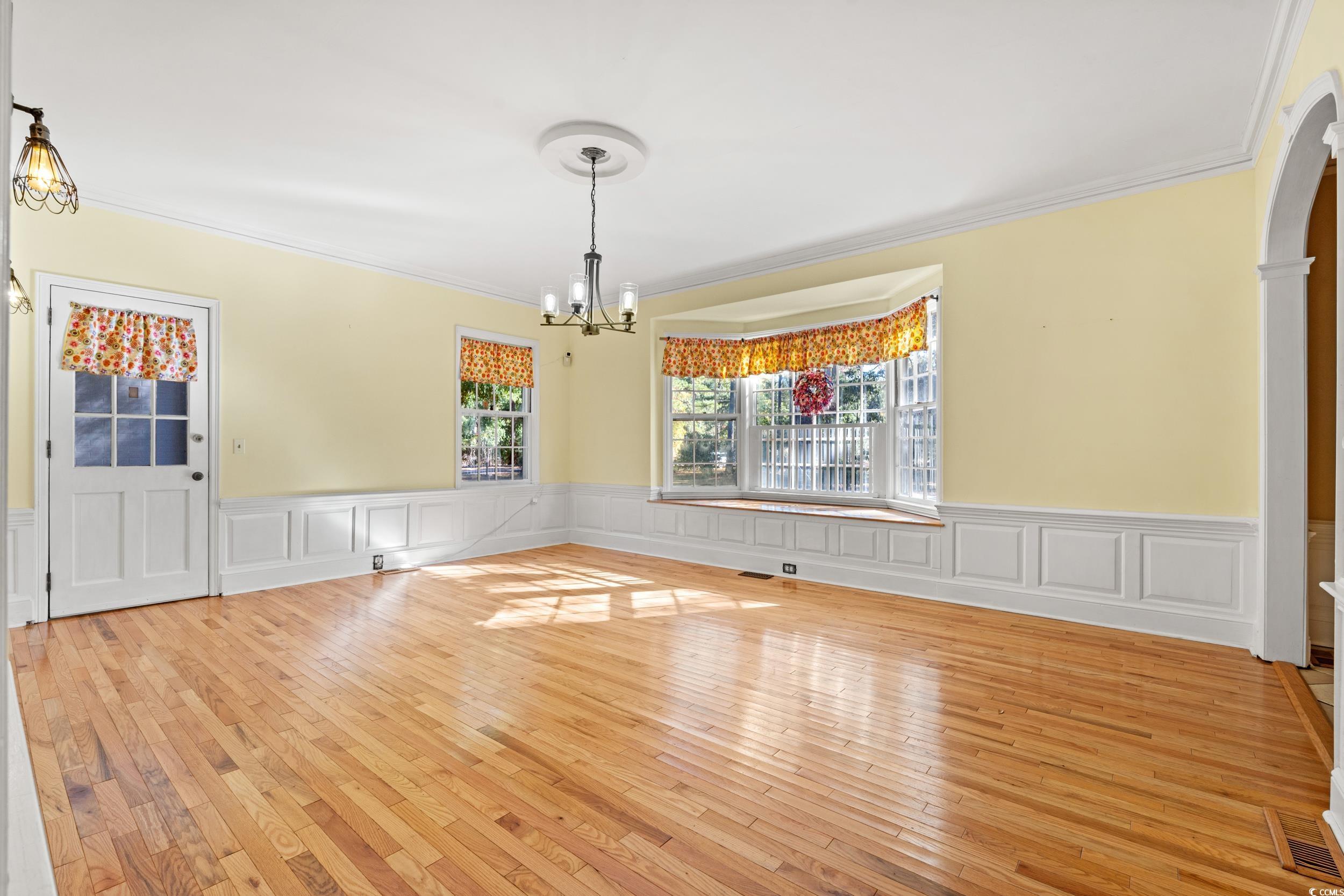607 North Main Street Nichols, SC 29581 - Photo 7 of 39 Unfurnished dining area featuring light wood finished floors, ornamental molding, a chandelier, a decorative wall, and wainscoting