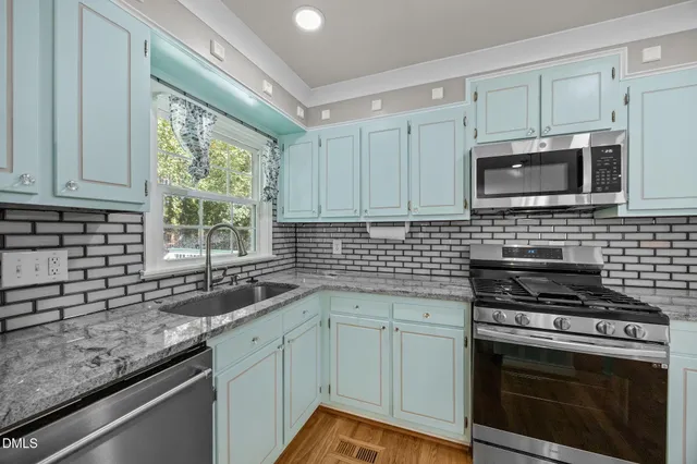a kitchen with granite countertop a sink stainless steel appliances and cabinets