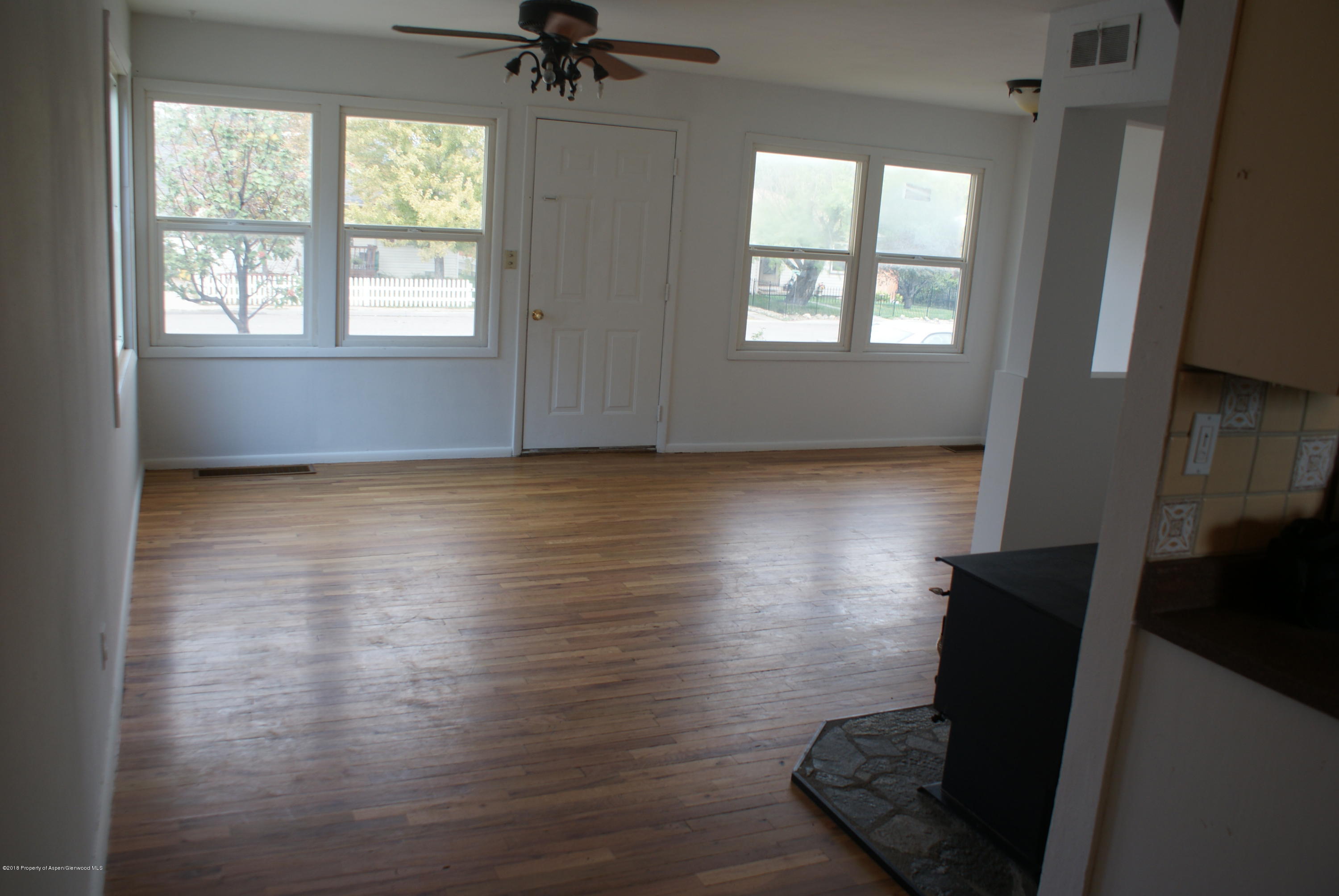 322 Elm Avenue Rifle, CO 81650 - Photo 4 of 13 a view of an empty room with wooden floor and a window