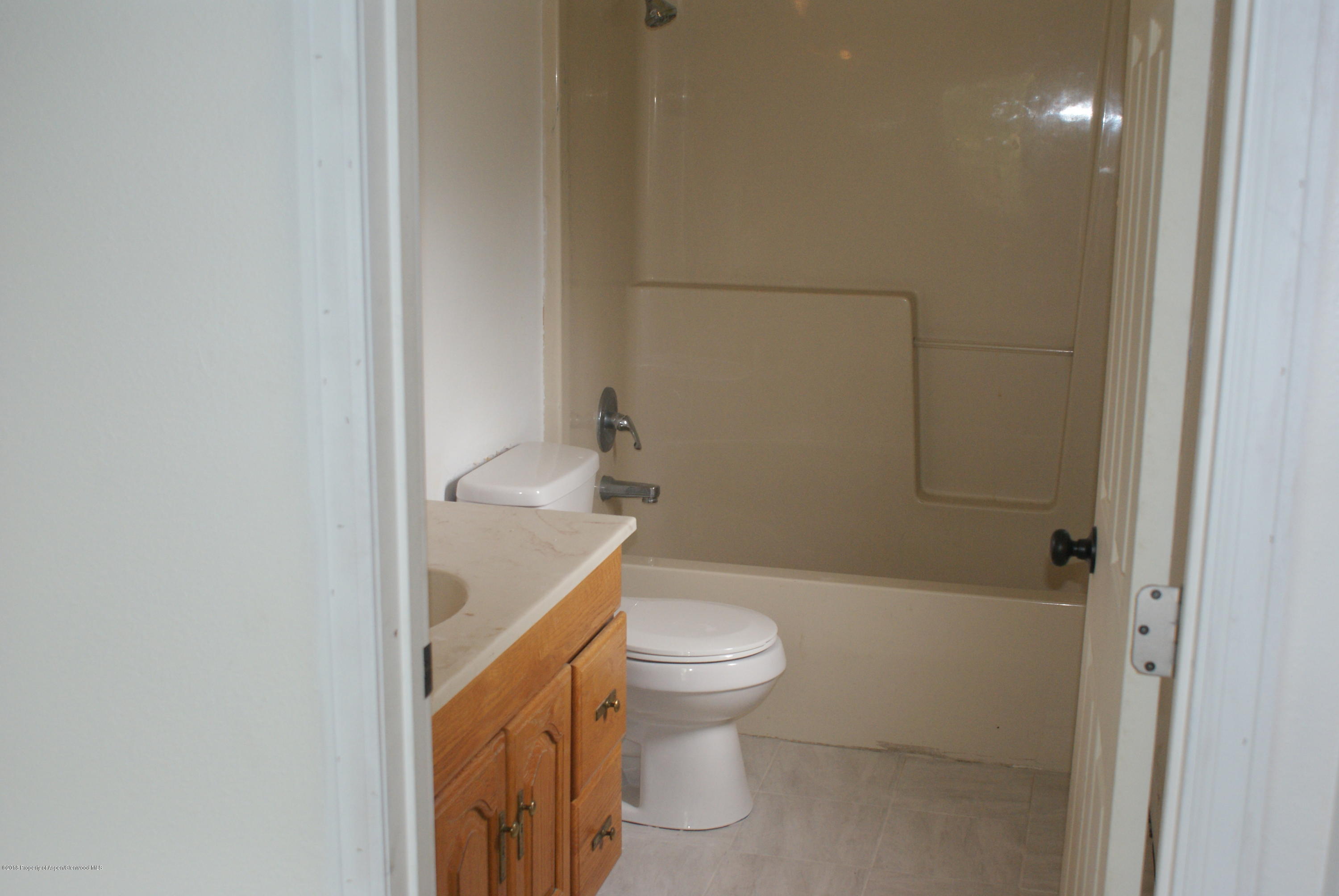 322 Elm Avenue Rifle, CO 81650 - Photo 7 of 13 a white toilet sitting next to a bathroom sink and vanity
