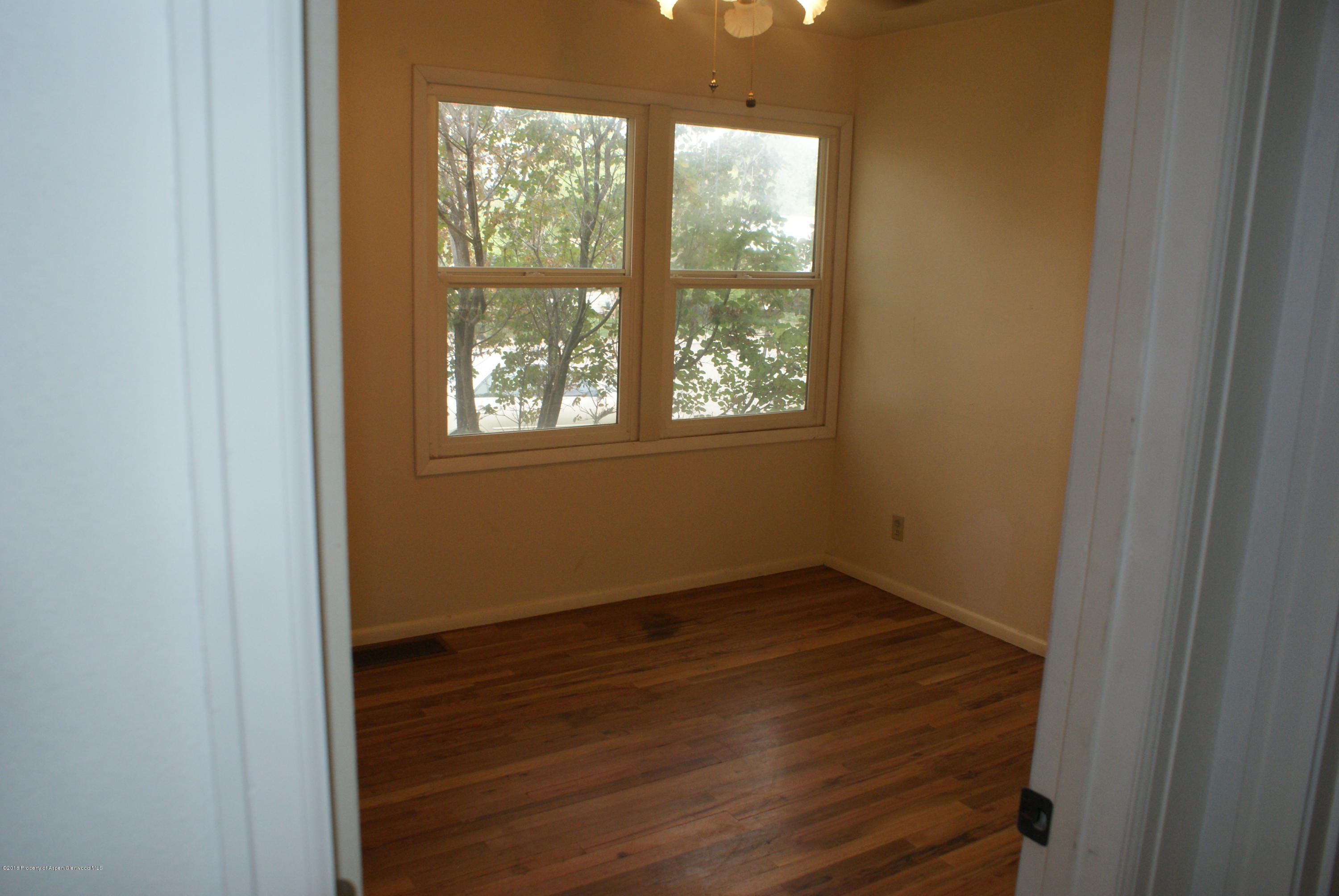322 Elm Avenue Rifle, CO 81650 - Photo 8 of 13 an empty room with wooden floor and windows