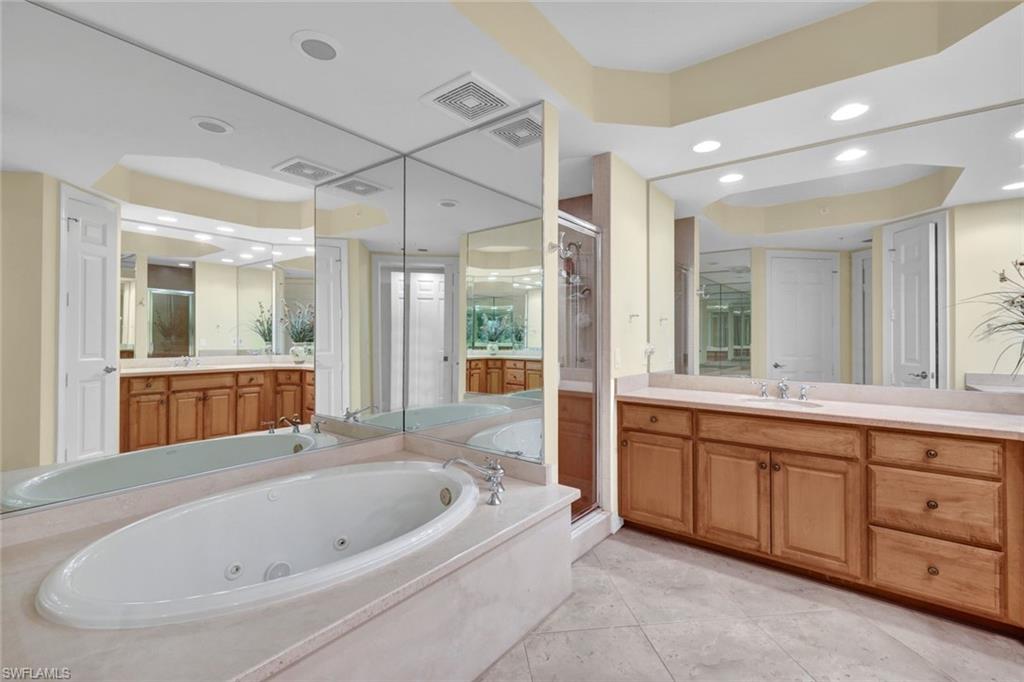 295 Grande Way, Unit 405 Naples, FL 34110 - Photo 17 of 40 a bathroom with a bathtub a double vanity sink and a large mirror