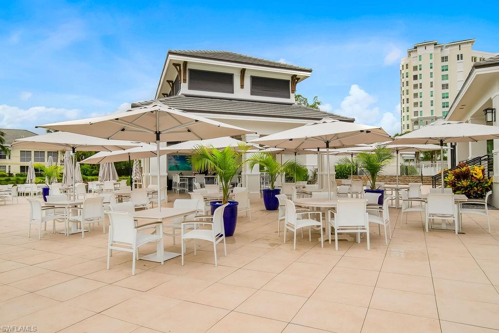 295 Grande Way, Unit 405 Naples, FL 34110 - Photo 27 of 40 a patio with a table and chairs under an umbrella