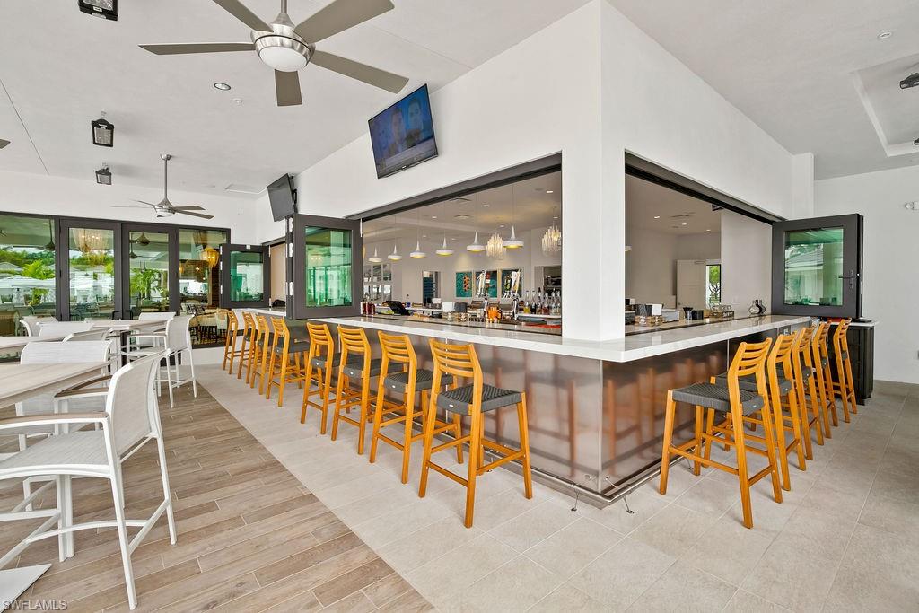 295 Grande Way, Unit 405 Naples, FL 34110 - Photo 29 of 40 an open kitchen with stainless steel appliances kitchen island granite countertop a table chairs and a view of living room