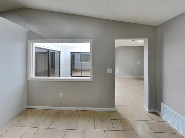a view of an empty room with window and chandelier fan