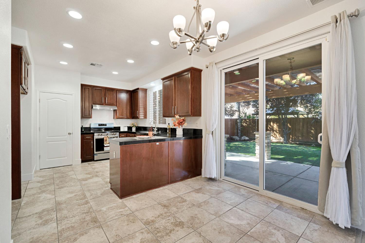 692 Blueberry Lane Madera, CA 93638 - Photo 12 of 44 a large kitchen with kitchen island a large window cabinets a sink and stainless steel appliances