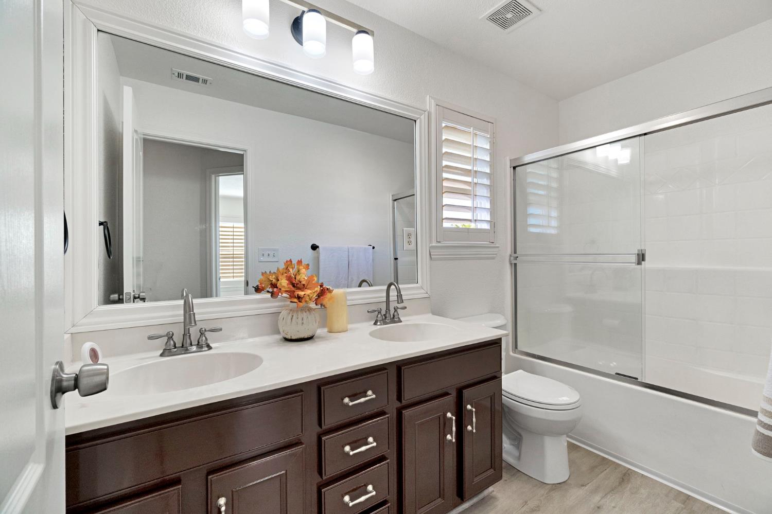 692 Blueberry Lane Madera, CA 93638 - Photo 22 of 44 a bathroom with a double vanity sink toilet mirror and shower
