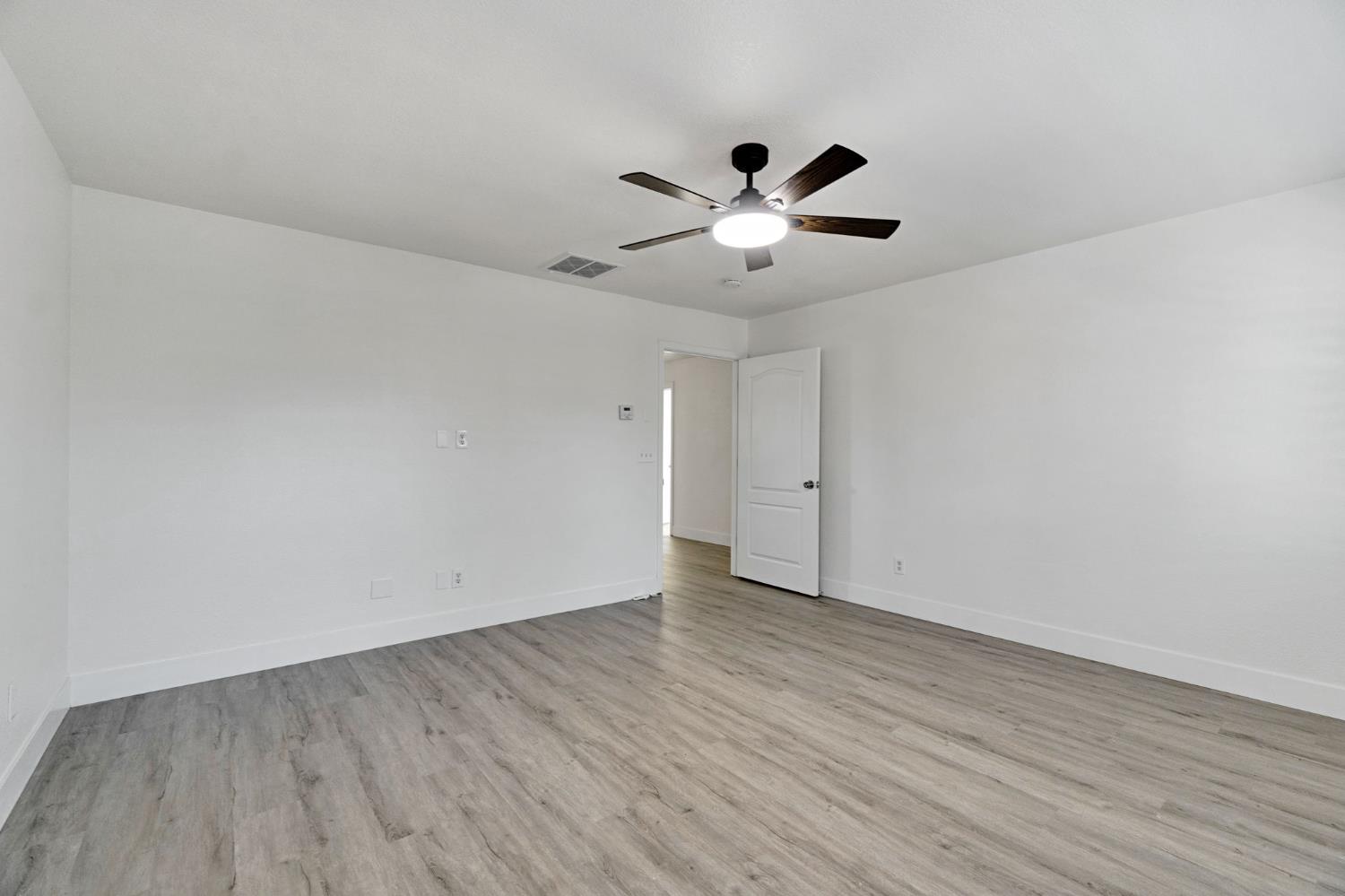 692 Blueberry Lane Madera, CA 93638 - Photo 30 of 44 an empty room with wooden floor and ceiling fan
