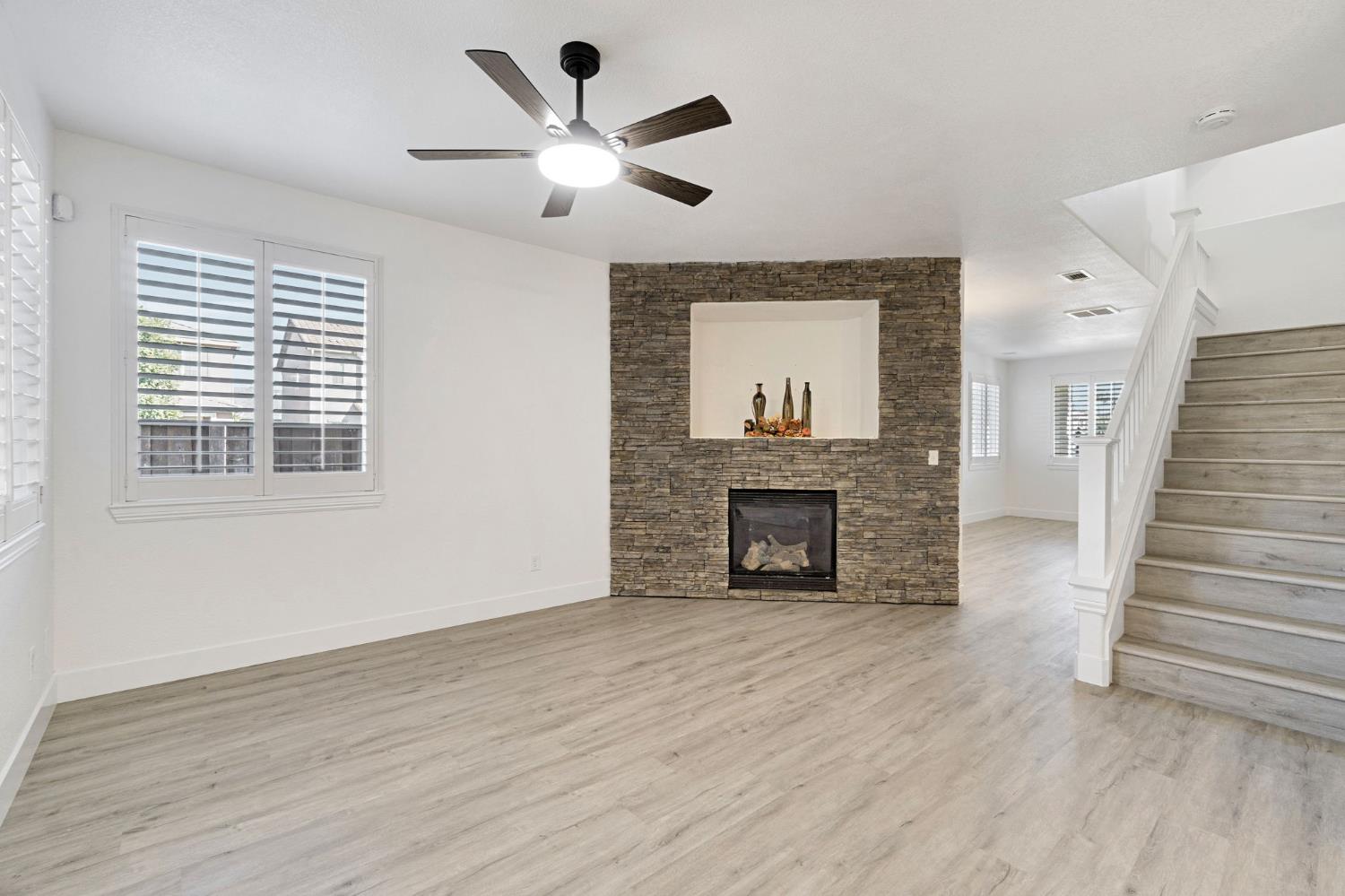692 Blueberry Lane Madera, CA 93638 - Photo 9 of 44 an empty room with wooden floor fireplace and windows