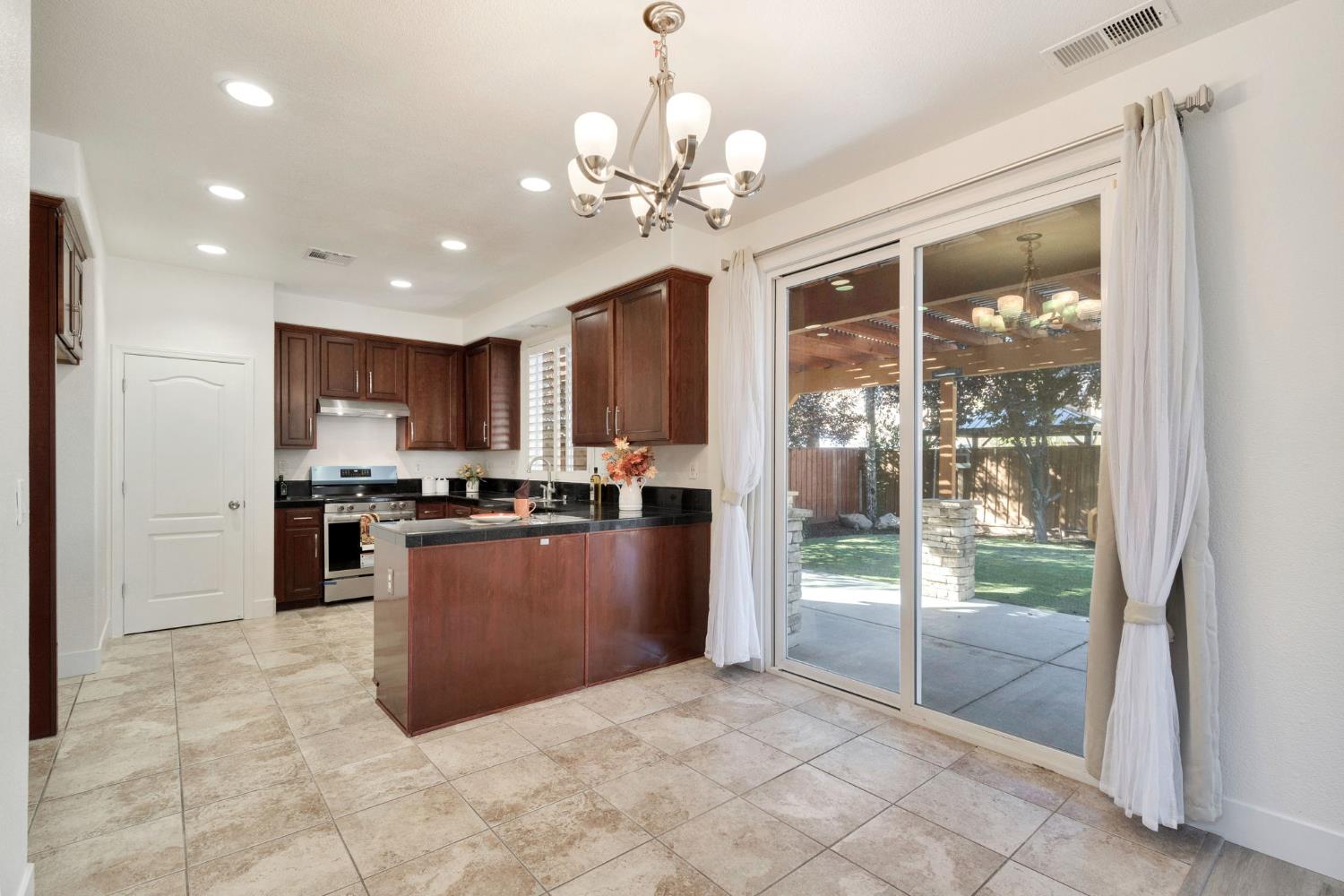 692 Blueberry Lane Madera, CA 93638 - Photo 10 of 44 a large kitchen with a large counter top stainless steel appliances and a chandelier