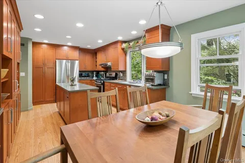 a kitchen with stainless steel appliances kitchen island granite countertop a table chairs and a wooden cabinets