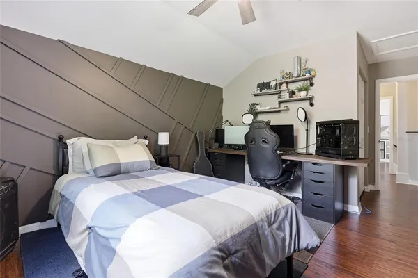 a bedroom with bed a flat tv screen and dresser