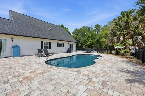 a swimming pool with yard and trees in the background