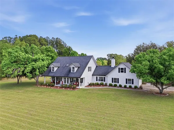 a aerial view of a house with swimming pool and large trees